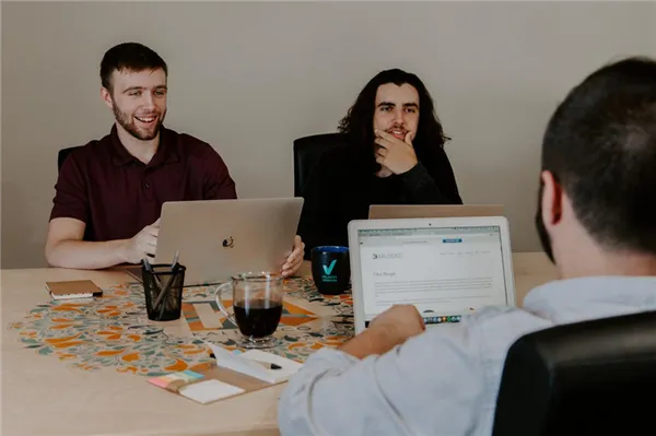 Трое мужчин работают за столом на ноутбуках
