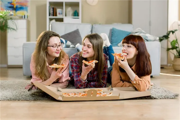 Три девушки едят пиццу лежа на полу