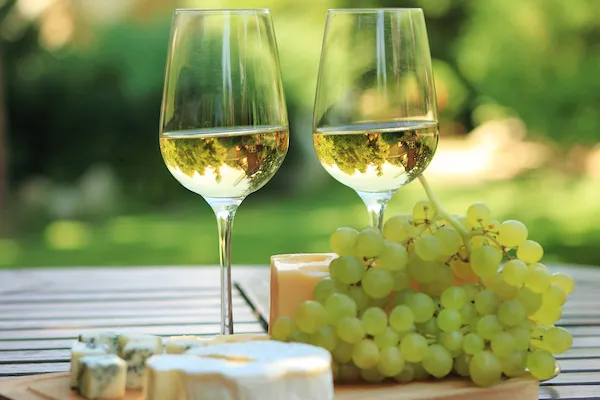 Бокалы с белым вином и виноградная гроздь на столе