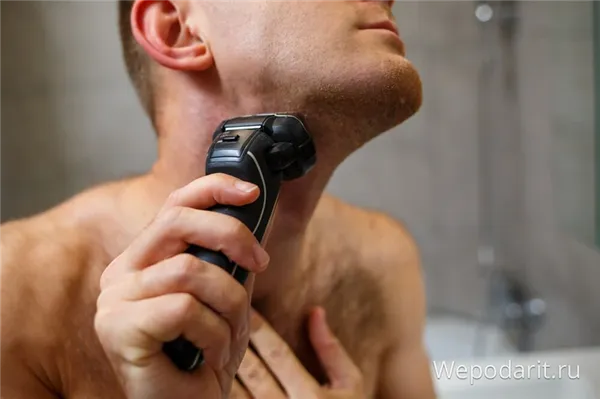 мужчина бреет лицо электробритвой