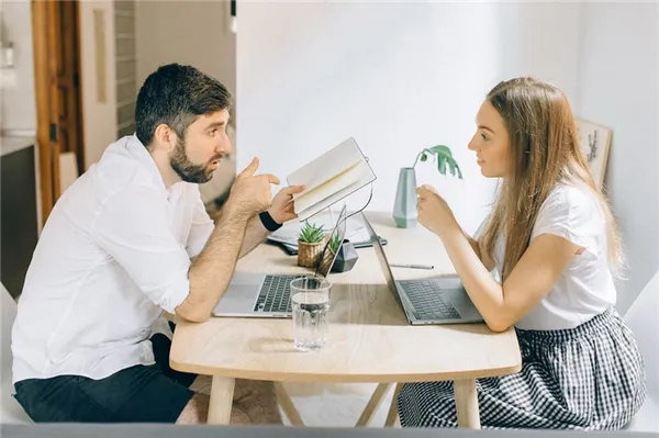 Мужчина и женщина разговаривают, сидя друг напротив друга с ноутбуками