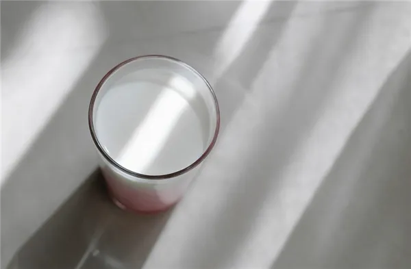 Стеклянный стакан с молоком стоит на столе