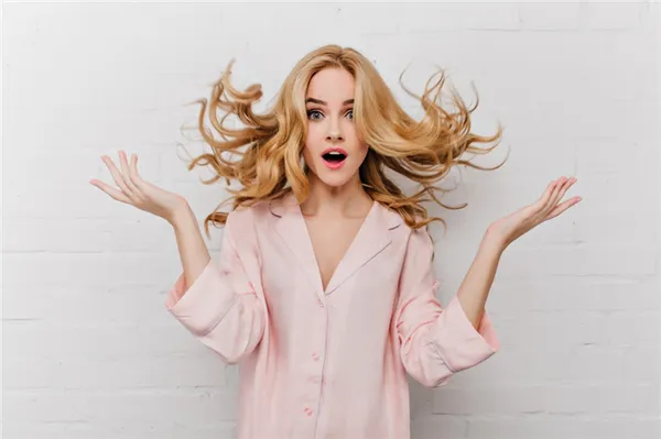 ecstatic-blue-eyed-woman-with-long-blonde-hair-posing-in-front-of-white-bricked-wall-indoor-shot-of-surprised-girl-in-beautiful-pink-pyjamas.jpg